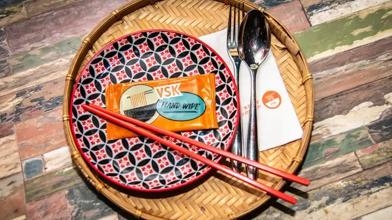 A Vietnamese Street Kitchen place setting: patterned plate, red chopsticks and a bamboo tray